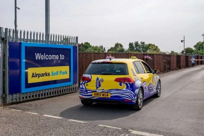 A yellow car with colorful graphics drives towards an entrance